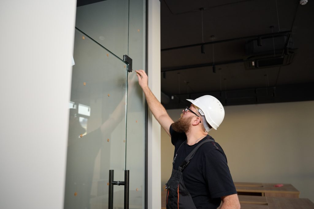 Bearded,Worker,Installing,Glass,Door,In,The,New,Office.,Construction